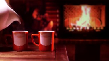 Şöminenin önünde Noel Baba resmi olan kupalar. Neşeli, rahat bir Noel ya da yeni yıl havası.