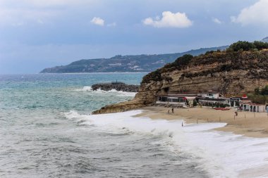 Akdeniz 'de kayalarla dolu bir kumsal Mavi gökyüzü ve dalgalarla
