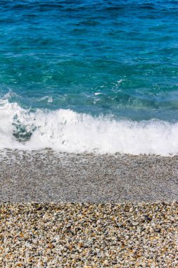 Calabria 'da taştan bir sahilde dalgalar kırılıyor.