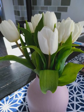 Beyaz laleler ilkbaharda mavi ve beyaz masa örtüsünde.