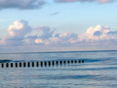 Bulutlu gökyüzü ve güneşli renklerle Baltık Denizi 'ndeki kumsal