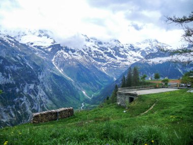 İsviçre 'de bir vadinin tepesinden inanılmaz bir manzara bulutlu gökyüzü ve karla kaplı dağlarla