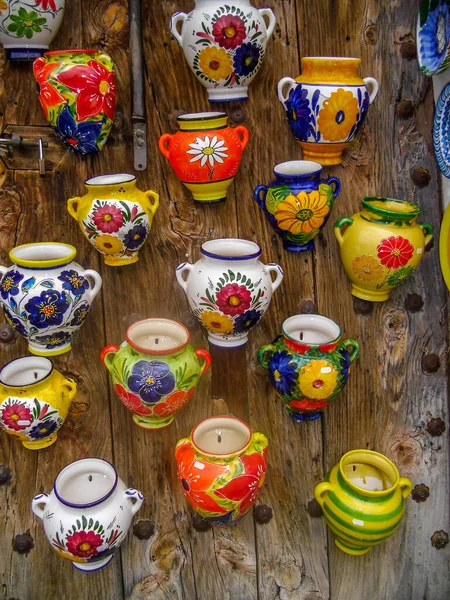 colorful ceramic souvenirs hanging on wooden wall in spain