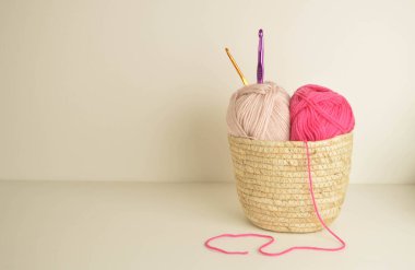 Pembe ve yumuşak pastel yün toplar sepetin içinde örgü kancası ve metin için yer var.