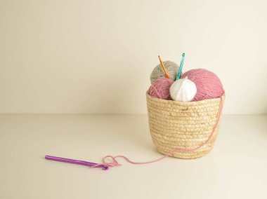 Pastel renkli yün toplar sepetin içinde, el işi için kancalarla.