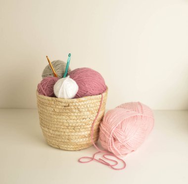 Pastel renkli yün toplar sepetin içinde, el işi için kancalarla.