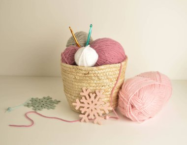 Pastel renkli yün toplar sepetin içinde, ahşap kar taneli el işleri için kancalarla örgü örüyorlar.