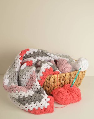 Örgü örülü yün toplar. Büyükanne kare battaniyesi sepette ve kancada.