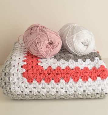 Örgü örülü yün toplar. Büyükanne kare battaniyesi sepette.