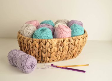 Örgü ve el işi için kancaları olan sepetteki pastel renkli yün toplar.