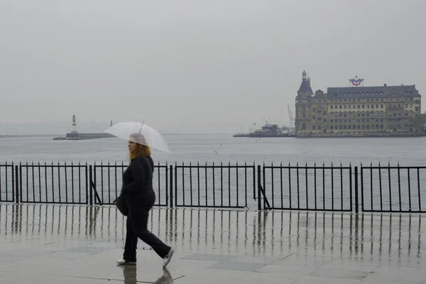 Una donna che cammina sulla strada sotto forti piogge Foto Stock