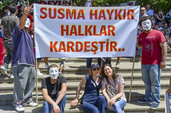 Guy Fawkes masked demonstrators with placards seen in Gezi Park. — Stock Photo, Image