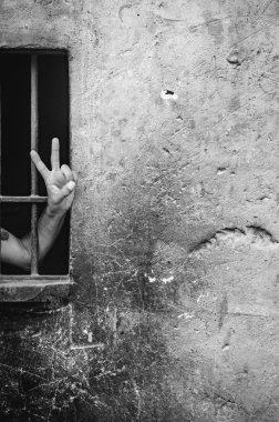 V parmaklıklar arkasında bir adam (zafer işareti) oturum açın. Arka plan.