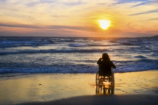Sonnenuntergang, macht Sightseeing am Strand zu einer Frau im Rollstuhl — Stockfoto