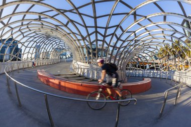 View of cyclist riding along the Webb Bridge in Docklands, Melbourne clipart