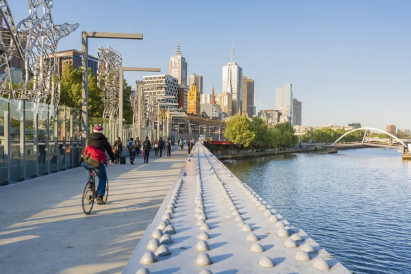 Cyklista a lidé pěšky přes most v centru Melbourne při západu slunce — Stock fotografie