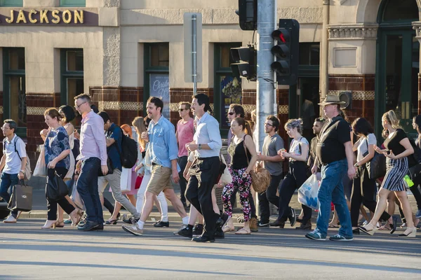 People walking across a busy crosswalk in Melbourne at sunset — Stock Photo, Image
