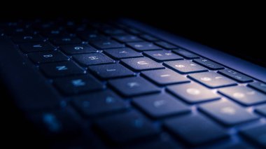 Karanlık bir odada gösterilen dizüstü bilgisayarın klavye arka ışığı