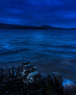 Lomond Gölü, Luss İskelesi 'nde. Karanlık, yağmurlu bir sabahta Inchlonaig' e bakıyor.