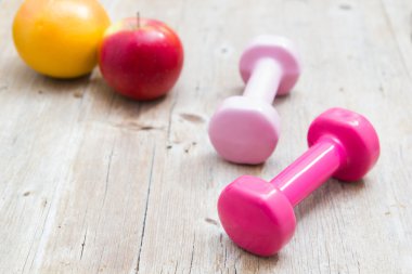 Spor fitness diyet kavramı ağırlık dambıl ve ahşap arka plan üzerinde meyve