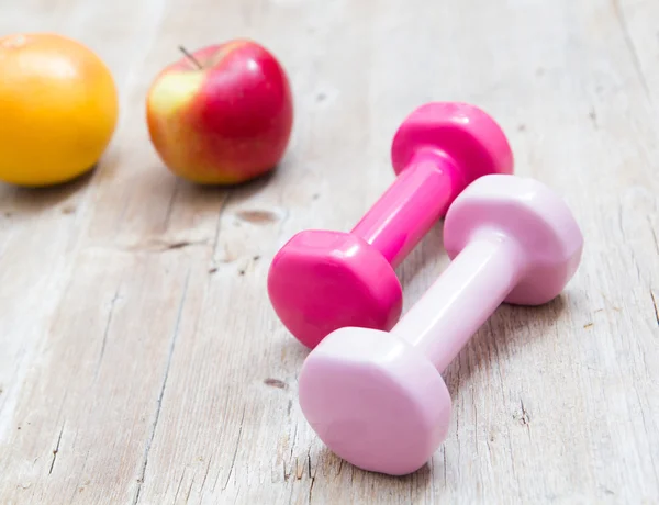 Spor fitness diyet kavramı ağırlık dambıl ve ahşap arka plan üzerinde meyve