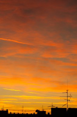 Kentsel günbatımı çatılarının antenas ve bulutlar