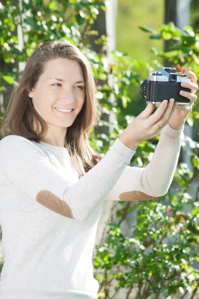 Szczęśliwa młoda kobieta fotograf za pomocą starego aparatu — Zdjęcie stockowe