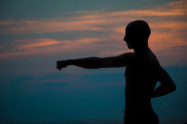 Siluetta di tramonto di un uomo praticando arti marziali Fotografia Stock