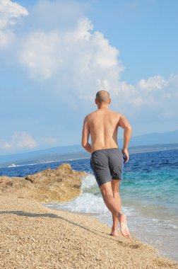 Sahilde koşu koşan genç adam