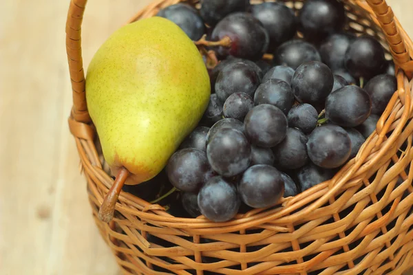 Panier plein de raisins avec poire sur le dessus Photos De Stock Libres De Droits