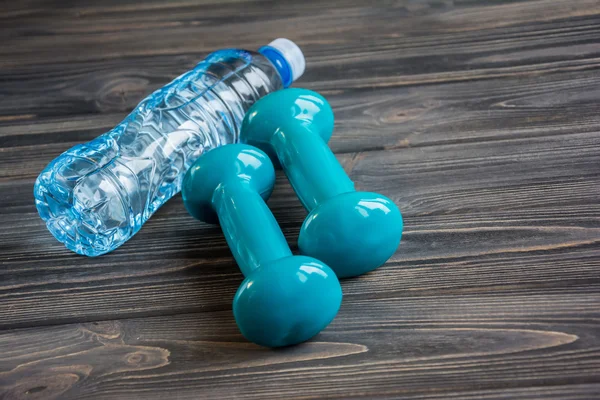 Dos pesas azules y una botella de agua — Foto de Stock