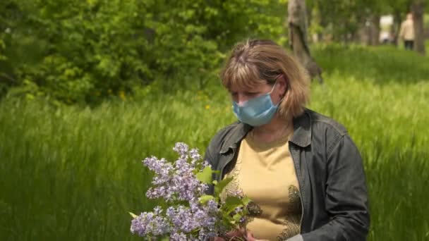 Весняний День Жінка Медичній Масці Букетом Квітів Сидить Лавці Парку — стокове відео