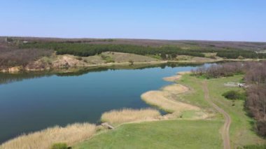 Baharda kırsal bir sahne. Göl, kır yolu ve orman hava manzarası.