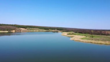 Resimli bir göletin havadan görünüşü. Gölün kıyısındaki kuru sazlıklar. Bahar geldi.