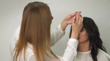 Profesyonel bir makyözün işi. Makyöz göz farı sürüyor.