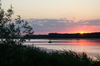 Nehrin üzerinde gün batımı. Nehirde kayıkta bir balıkçı görebilirsiniz. Dinyeper Nehri Ukrayna