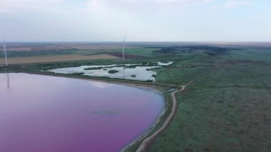 Gün batımında pembe bir gölün kıyısında bir rüzgar türbini. Lemuria Gölü, Ukrayna 'nın Kherson bölgesinde yer alan bir göldür. Hava görünümü