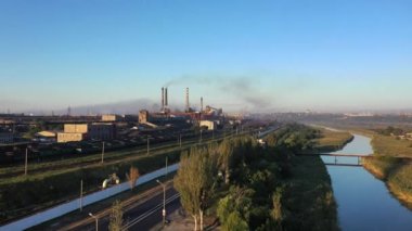Kuş bakışı bir çelik fabrikası. Endüstriyel bölgeye yakın bir nehir ve yol var. Çevre kirliliği
