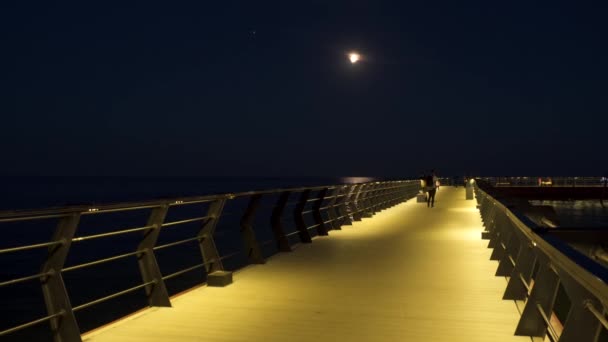 Mariupol Ukraine 2021年10月17日 夜の海の桟橋 人々は桟橋に沿って歩く 月は空に 月は海に見えます — ストック動画
