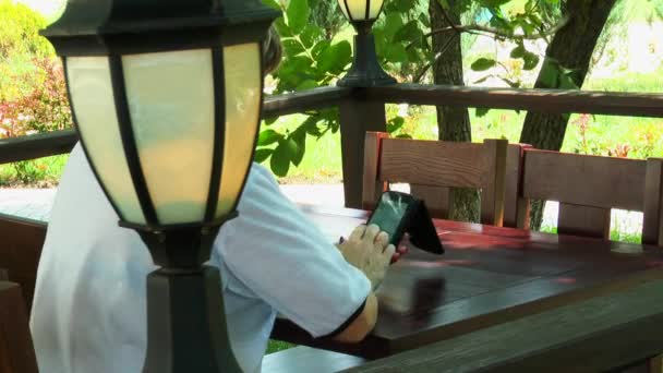Vrouw in de straat café kijken naar foto's op een smartphone — Stockvideo