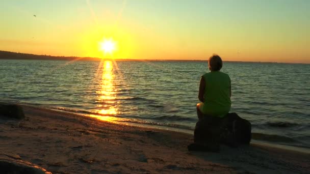 Una mujer mirando el amanecer sobre el mar — Vídeos de Stock