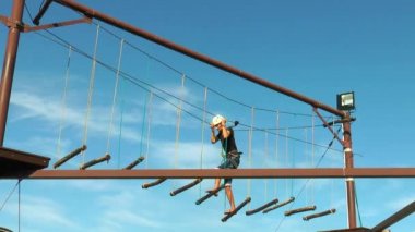 Genç adam arka plan mavi gökyüzü üzerinde bir ip yolda gidiyor