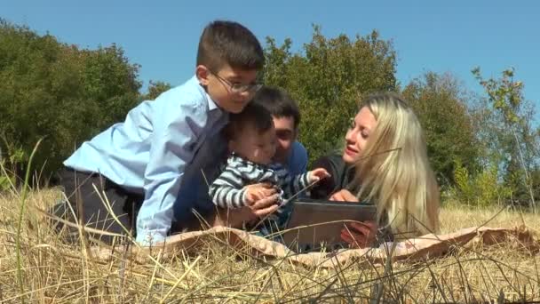 Свадебная пара с детьми, лежащими в парке — стоковое видео