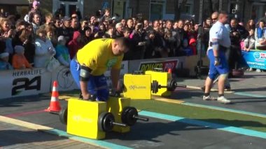 Atlet, her biri 150 kg ağırlığında demir bavul taşır.