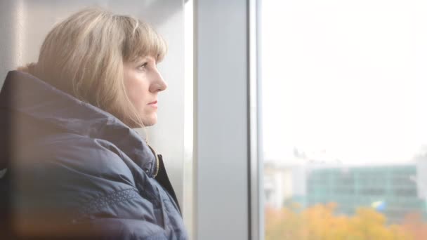 En kvinna tittar ut genom fönstret — Stockvideo