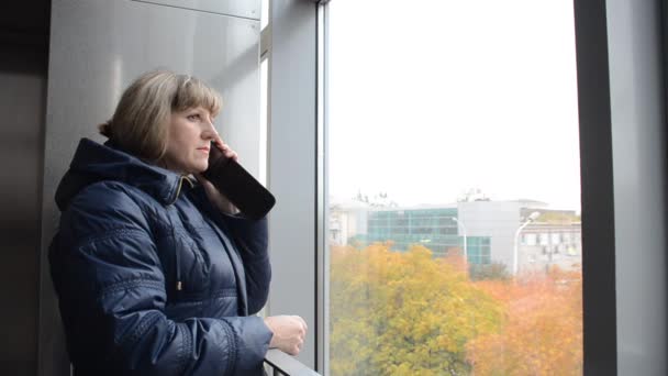 La mujer en la ventana hablando por teléfono — Vídeo de stock