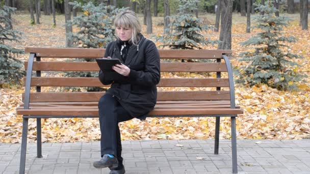 Une femme sur un banc avec la tablette — Video