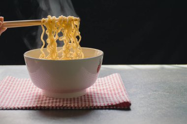Buhar ve duman ahşap masada hazır şehriye ve doğa ışığı ve siyah arka plan, seçici odaklanma. Bu elverişli ve ucuz bir besin, ama sık sık yemek sağlık için iyi değildir..