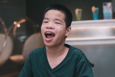 Asyalı engelli çocuk restoranda tatlı meyve suyu, eğitim çağında yaşam, normal insanlar gibi hayat tecrübesi, mutlu engelli çocuk ve engelli çocuk bakımı konsepti.