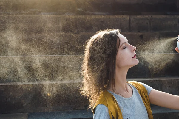 Genç kadın sprey yüz termal su ile. Zevk, cilt bakım kavramı.